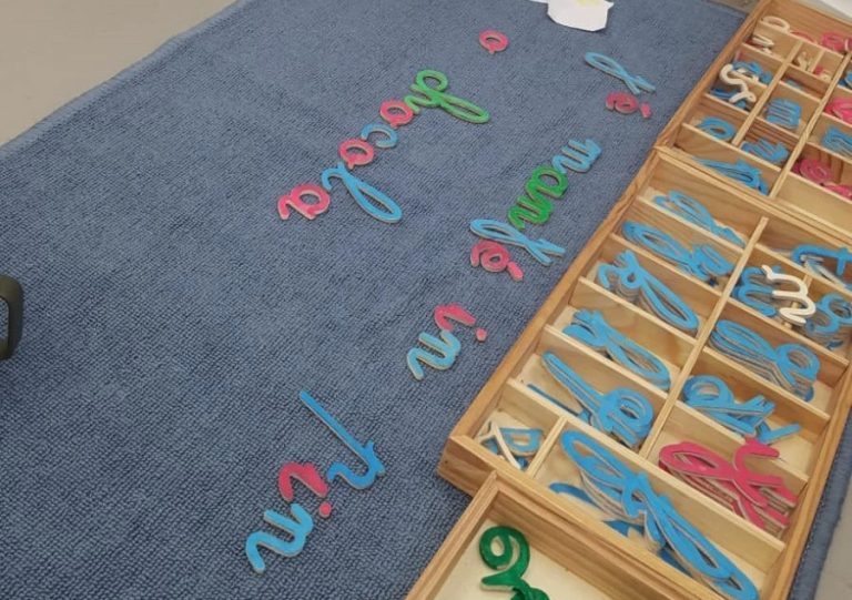 Lettres cursives au sol sur un tapis dans la classe